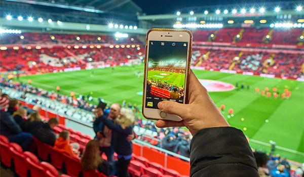A Liverpool fan taking a photograph of Anfield