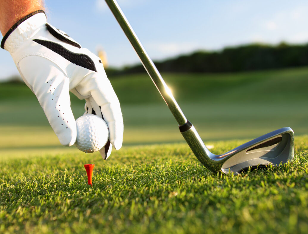 A golfer placing the ball on the tee.